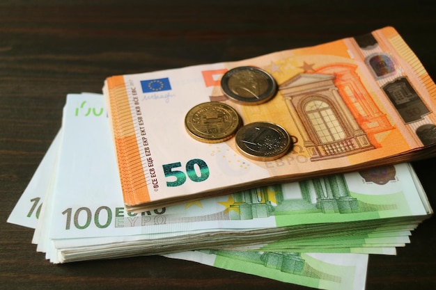 Bündel von Euro-Banknoten und -Münzen auf dunklem Hintergrund