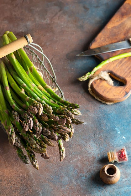 Bündel von frischem selbst angebautem Bio-Spargelgemüse in einem Korb, der bereit ist, gesundes veganes Essen auf einer Steinmauer zu kochen.