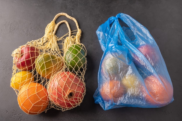 Bündel von gemischtem Bio-Obst, Gemüse und Gemüse in einer Schnur-Tasche und Plastik auf dunklem Hintergrund.