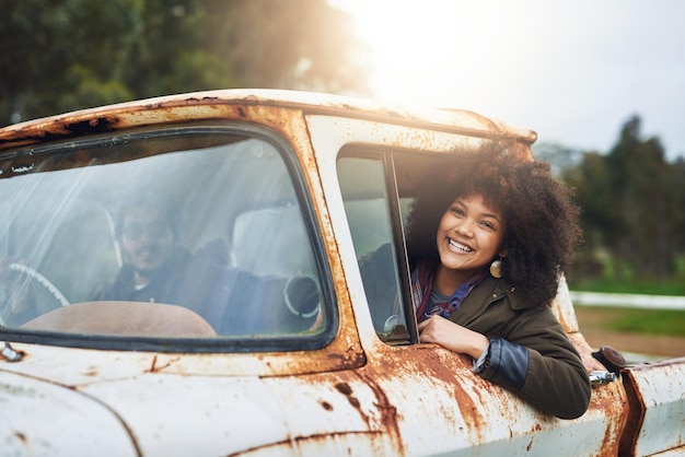 Bueno, nunca dejes de explorar Foto de una joven feliz sentada en un viejo camión oxidado