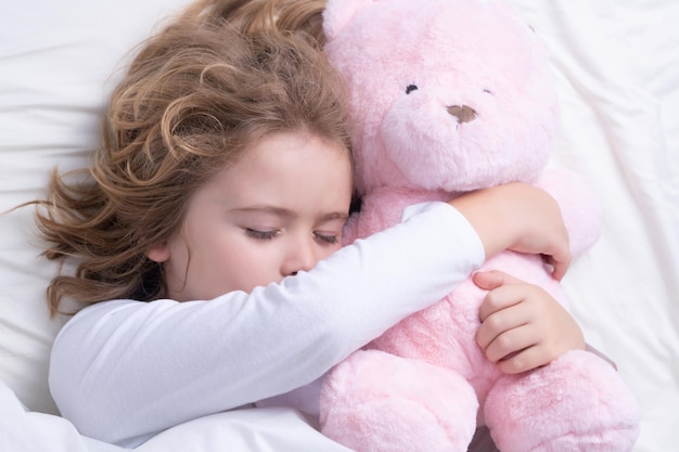 Buenos días duerme niño durmiendo en la cama con un oso de peluche de juguete lindo niño durmiendo bien solo en