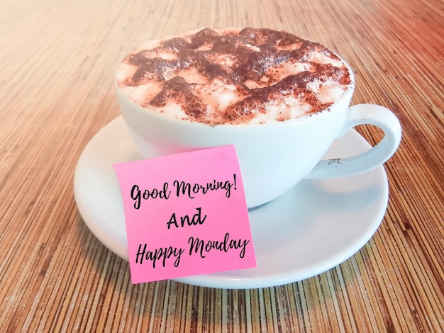 Foto buenos días y feliz lunes texto escrito en una nota de palo con taza de chocolate caliente