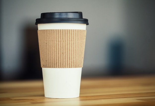 Buenos días. Taza de café para llevar en mesa de madera.