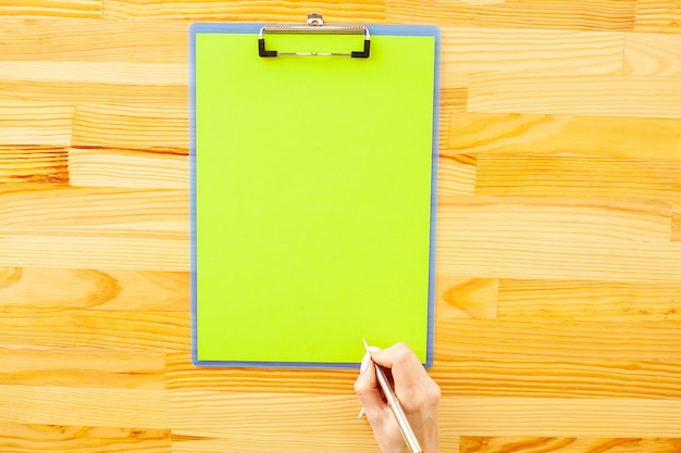 Büro-Hand, die einen Ordner mit einem grüne Farbpapier und -stift hält