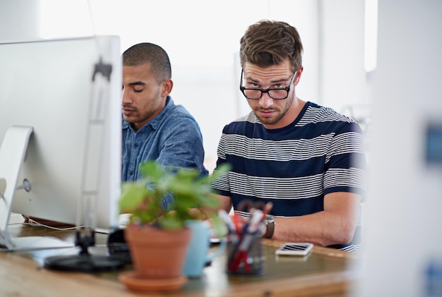 Büro und Porträt mit Computer im Schreibtisch mit Online-Forschung für kreatives Projekt als Grafikdesigner Angestellte Menschen und ernsthaft auf dem PC für Geschäftswachstum mit Frist in Startup-Unternehmen