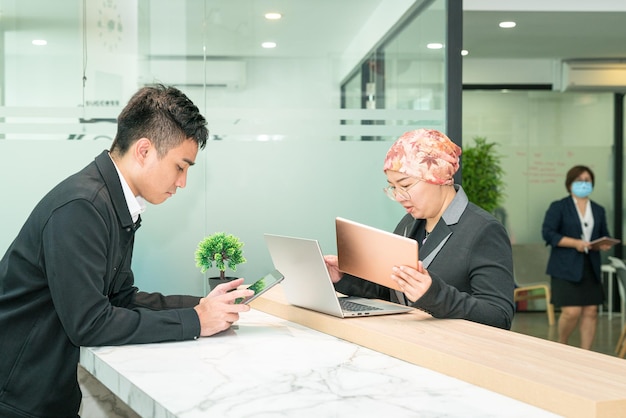 Büroangestellte, die an Laptop-Tablet und Smartphone arbeiten