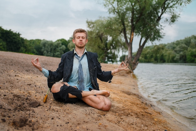 Büroangestellter, der am Strand in der Yoga-Pose, einsame Insel sitzt. Geschäftsrisiko, Zusammenbruch oder Insolvenzkonzept