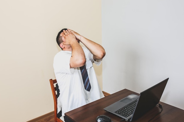 Büroangestellter im weißen Hemd. Berufsbedingter Burnout. Schlechte Arbeitsbedingungen. Unglücklicher Manager mit Laptop. Sommerhitze. Termine einhalten. Stressiger Job am Schreibtisch. Verzweifelter Mann.