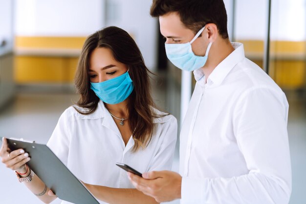 Büroangestellter mit Gesichtsmaske, der im Büro arbeitet Das Konzept zur Verhinderung der Ausbreitung der Epidemie