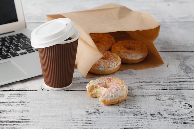 Büroarbeitsplatz mit Frühstück. Donuts und Kaffee