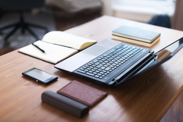 Büroarbeitsplatz mit Laptop-Smartphone und Notebook auf Holztisch