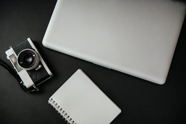 Büroausstattung Laptop Notebook und Kamera auf schwarzem Hintergrund Draufsicht von oben