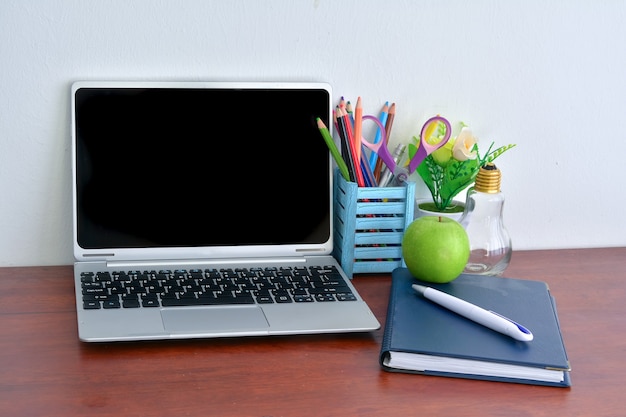 Bürobedarf, Laptop mit Notebook und Apfel auf Holztisch