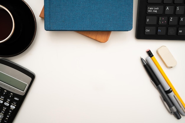 Bürobedarf über Schreibtisch mit Tastatur und Brille und Kaffeetasse zum Arbeiten aus der Ferne sortiert