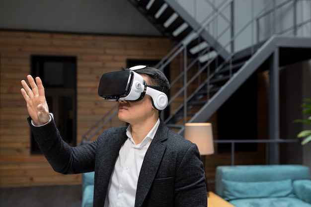 Büroleiter in formeller Kleidung mit Virtual-Reality-VR-Brille, die Online-Bilder im modernen Büro durchläuft Augmented-Reality-Konzept Menschen und Technologie