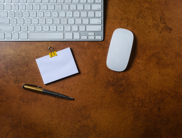 Bürotisch mit Notizblock, Computertastatur, Maus und Stift. Sicht von oben.