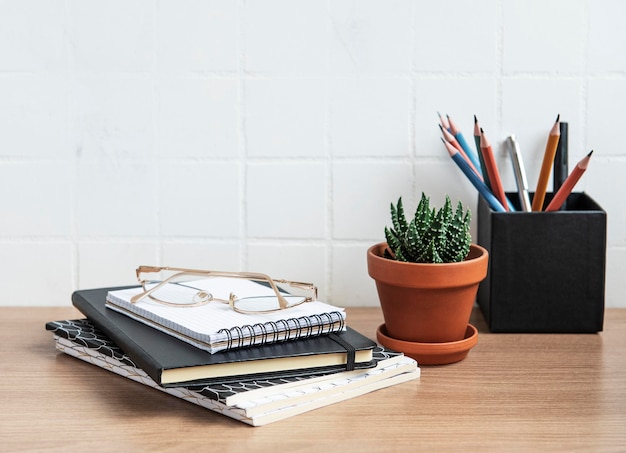 Bürotisch mit Notizbüchern, Vorräten und Zimmerpflanzen