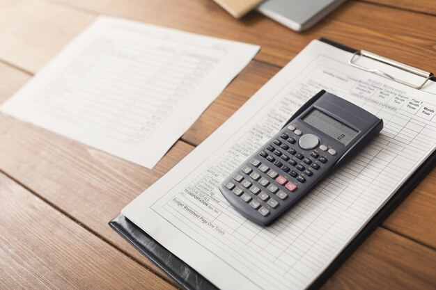 Bürotisch mit Taschenrechner und Dokumenten. Finanzieller Hintergrund, ein Konto zählen und bezahlen, Platz kopieren