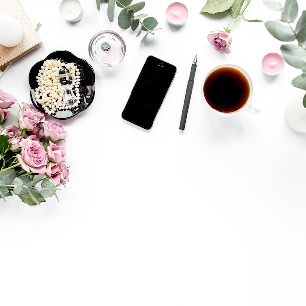 Bürotisch Schreibtisch Arbeitsbereich mit Pinsel Laptop rosa Blumen Telefon auf weißem Hintergrund flach compo