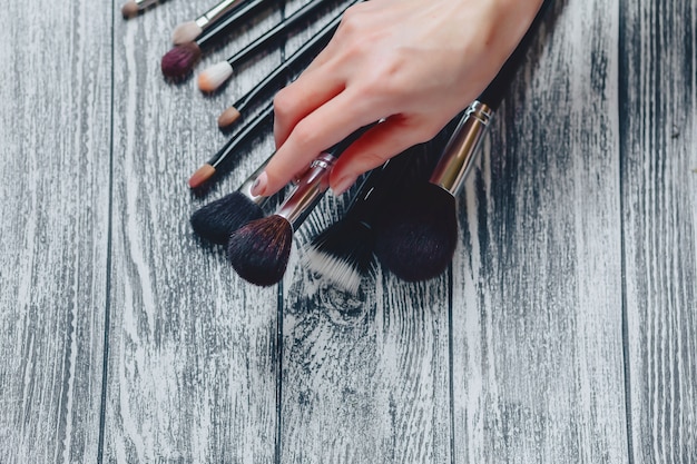 Bürsten für Make-up in den Händen auf hölzernem Hintergrund