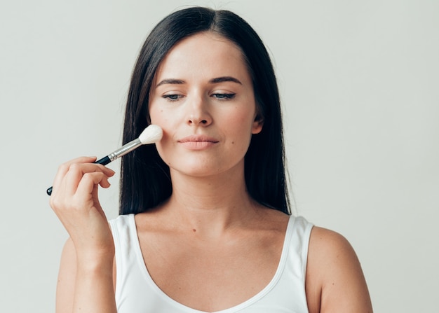 Bürsten Sie Make-up-Frauengesicht gesunde Haut natürliches Make-up-Pulver. Studioaufnahme.