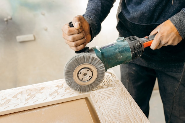 Bürsten von Holz mit einem elektrischen Rotationsbürstenschleifer. Holzbearbeitung.