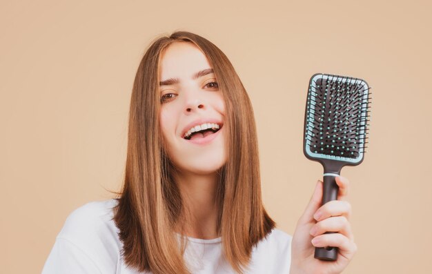 Bürstendes Haarporträts junge Frau, die gerades natürliches Haar mit dem Kammmädchen bürstet, das lange Gesundheit kämmt