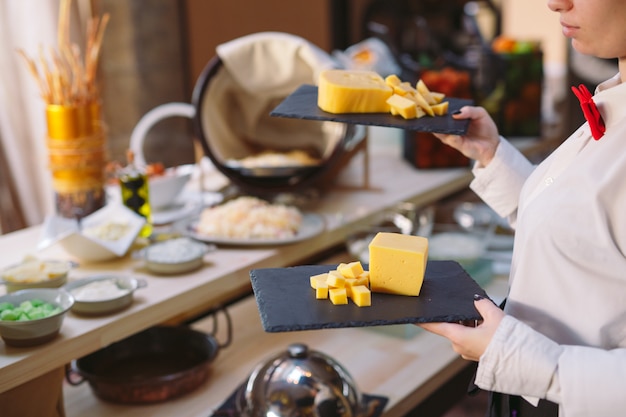 Foto buffet. el camarero sostiene un plato de queso en lonchas.