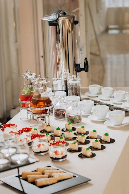 Buffet de postres con deliciosos pasteles dulces y refrigerios de café con elegantes bancos de limonada y té.