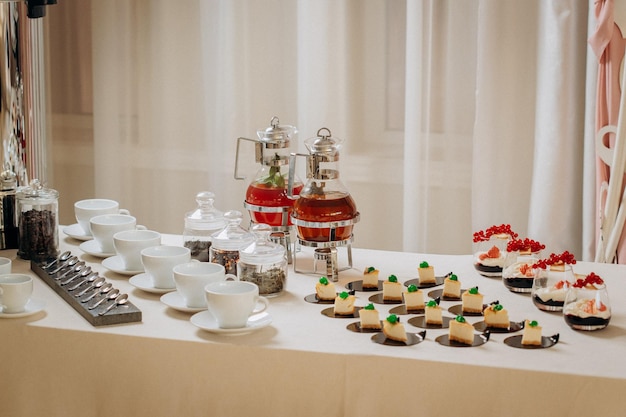 Buffet de postres con deliciosos pasteles dulces y refrigerios de café con elegantes bancos de limonada y té.