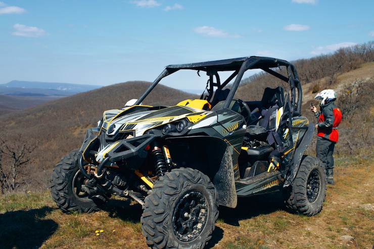 Foto buggy estacionado en las montañas y conductor en equipamiento deportivo de pie detrás