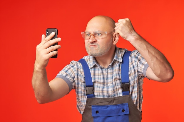 Foto builder hält ein telefon in der hand und zeigt seine faust in die kamera