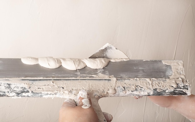 Builder verputzt mit einem Spachtel und glättet die Wand mit Gips