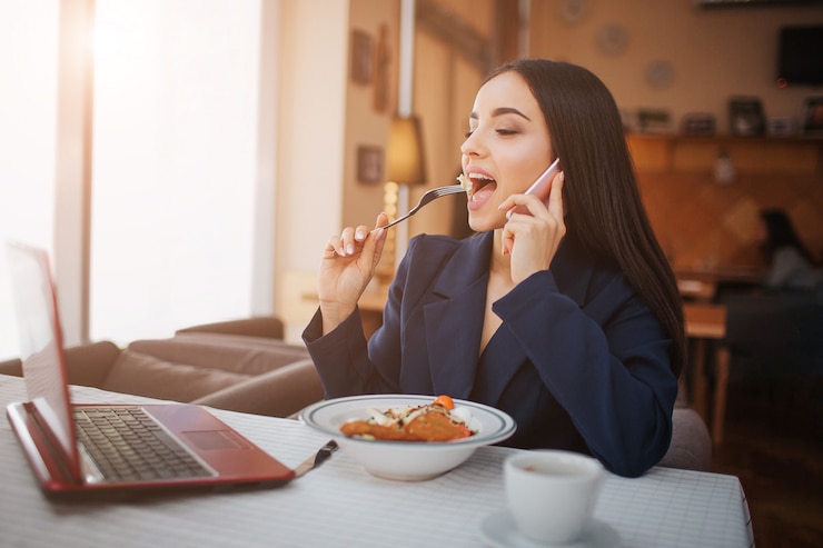Foto buisnesswoman jovem alegre trabalhar no restaurante, ela olha para a tela e come salada