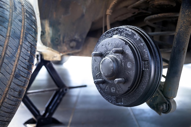 Un buje trasero del automóvil después de quitar un neumático y una rueda, mantener un sistema de frenos y ruedas, un elevador de automóvil para cambiar una rueda de automóvil, Toma de primer plano