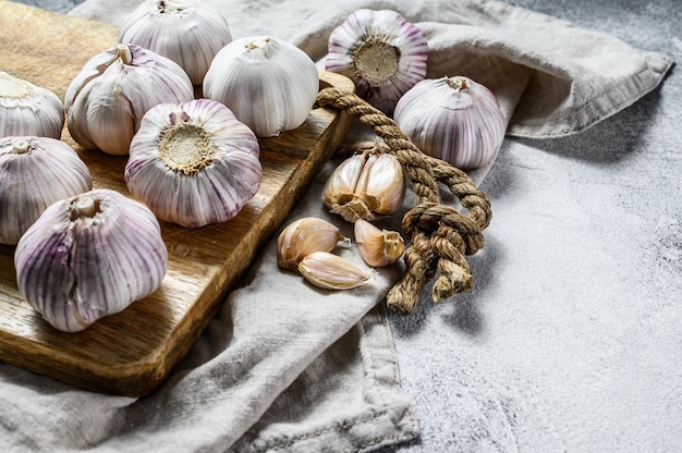 Bulbo de ajo y dientes de ajo en una tabla para cortar madera. El concepto de alimentación saludable. Fondo gris Vista superior