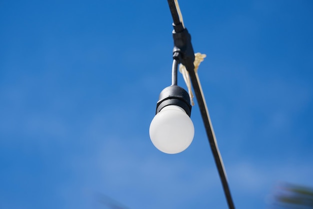 Bulbo de luz en un cable con cielo azul en el fondo