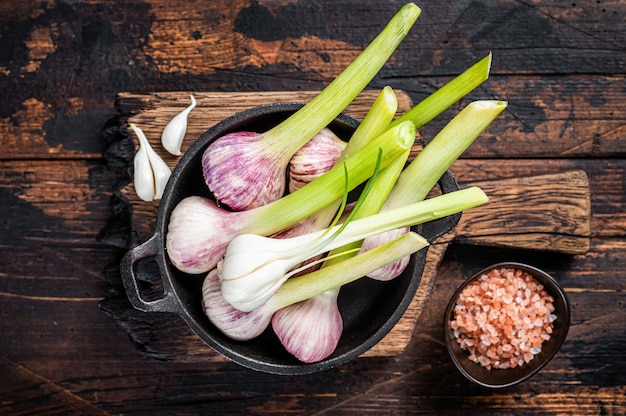 Bulbos de ajo tiernos de primavera cruda y clavo de olor en tablero de mármol