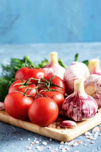 Bulbos de ajo de tomates frescos en tablero de madera Foto vertical