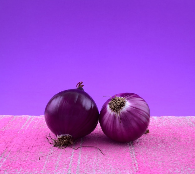 Bulbos de cebolla morado bodegón estilo fine art colorido vegetal culinario en rosa con azul lila