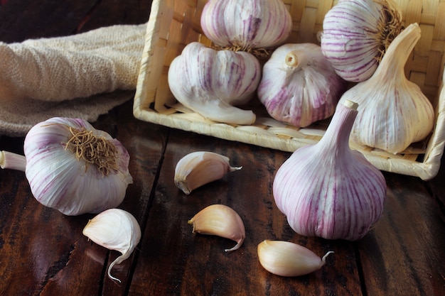 Bulbos de alho dentro cesta de palha, na mesa de madeira rústica