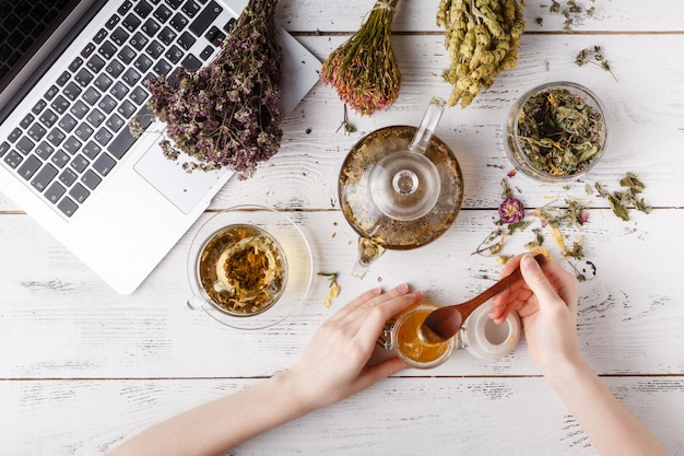 Foto bule com chá de ervas na mesa da cozinha e mulher escrever receita