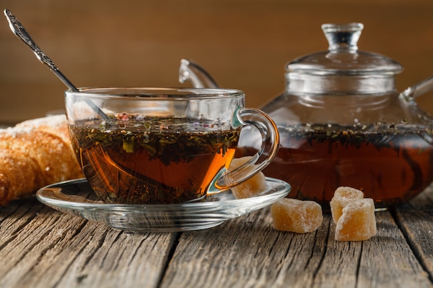 Bule de vidro e xícara de chá de ervas na mesa de madeira velha