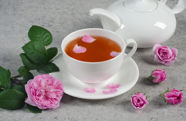 Foto bule e xícara de chá com pétalas e botões de rosa em uma mesa texturizada cinza. ãƒâƒã‚âƒãƒâ‚ã‚â ãƒâƒã‚â‚ãƒâ‚â¡lose-up.