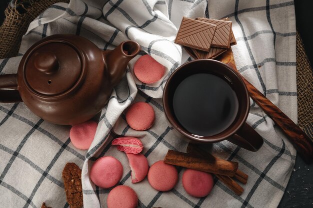 Bule e xícara em pano de cozinha com macarons rosa dispersos