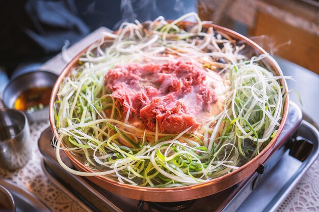 Bulgogi de barbacoa de ternera en el restaurante de Corea del Sur en el estilo de vida de Seúl cocina de comida coreana fresca en una sartén de cobre con una parrilla en rodajas cerca del espacio de copia