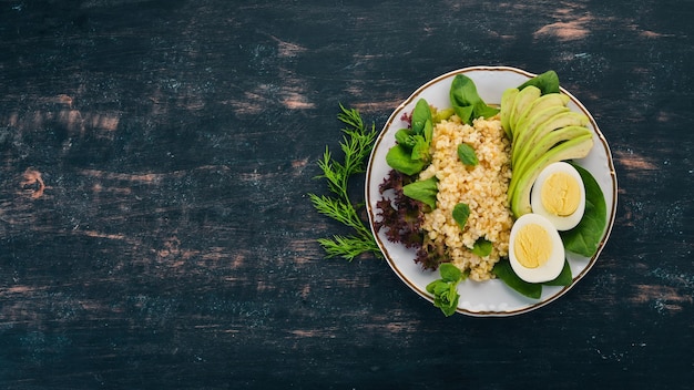 Bulgur com espinafre de abacate e ovo cozido em um fundo de madeira vista superior copiar espaço