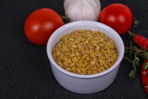 Bulgur crudo en el bol con tomates y ajo