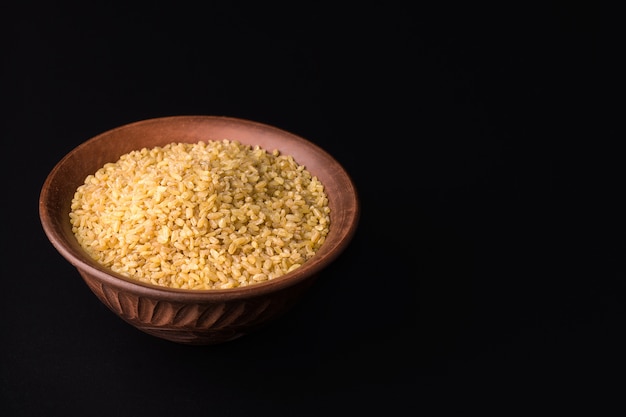 Bulgur crudo en un cuenco de barro negro