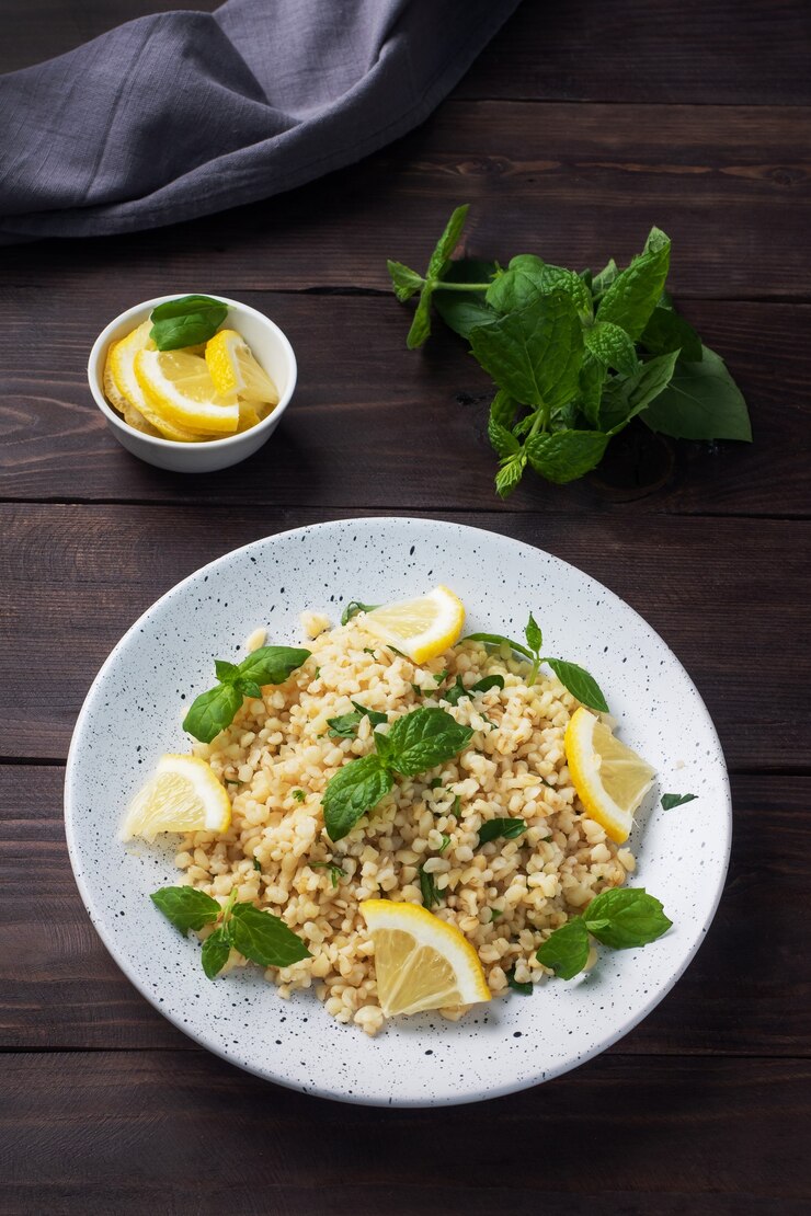 Bulgur hervido con limón fresco y menta en un plato. Un plato oriental tradicional llamado Tabouleh. fondo de madera oscura.